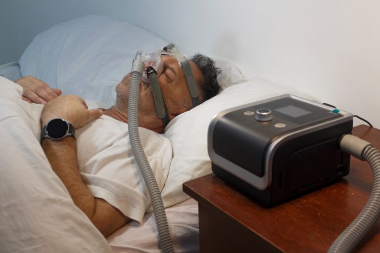 Man sleeping with a CPAP mask connected to a bedside breathing machine